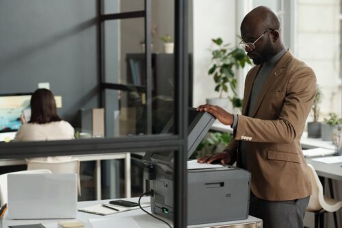 man standing at printer using managed print solutions